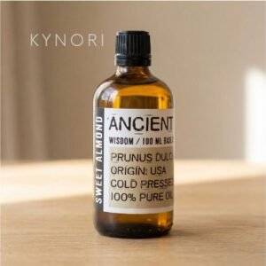Aceite base de almendras dulces KYNORI en frasco de vidrio ámbar sobre superficie de madera, estética natural y minimalista